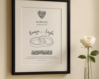 Peut inclure: Impression encadrée avec un cadre noir, avec les noms "Hamza & Layla" et des alliances. Une rose blanche dans un vase en verre est posée sur une surface blanche. L'impression comprend des dates et du texte.