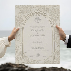 Puede incluir: Un certificado de boda decorativo con diseños florales y de arco. Los nombres "Yusuf Alvi & Mariam Noor" se muestran en una escritura elegante. El certificado es sostenido por dos personas, con el océano de fondo.