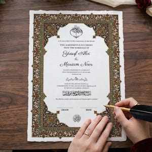 May include: A rectangular Islamic marriage certificate with a decorative border featuring intricate floral patterns in gold, red, and green. The document includes printed text, calligraphy, and blank lines for signatures, being signed with a black quill pen.