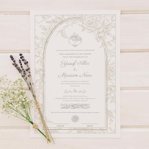 May include: A wedding certificate with floral border and the names Yusuf Alvi & Mariam Noor. The certificate is on a white wooden surface, with sprigs of lavender and baby's breath.