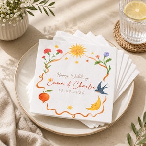 May include: A stack of square white paper napkins featuring a watercolor illustration of a sun, moon, flowers, a pomegranate, and a bird. The text reads Happy Wedding, Emma & Charlie, and 12.08.2026 in a decorative script and sans-serif font.