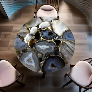 Könnte beinhalten: Ein runder Tisch aus poliertem Achatstein mit Blautönen, Weiß und Braun, mit goldenen Akzenten. Der Tisch ist von drei Stühlen mit hellrosa Sitzflächen und dunklen Holzrahmen umgeben. Der Text "StoneGalleryKing" ist auf dem Tisch zu sehen.