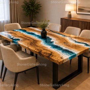 Könnte beinhalten: Ein großer Esstisch aus Holz mit einem blauen Harzfluss-Design. Der Tisch hat eine natürliche Holzmaserung mit einem blauen Epoxidharzfluss in der Mitte. Er wird von einem schwarzen Metallsockel getragen und ist von sechs beige gepolsterten Stühlen umgeben.