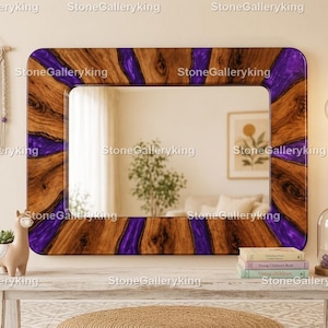 Può includere: Uno specchio rettangolare in legno con intarsio in resina viola. Lo specchio ha un motivo a venature naturali e viene esposto su un tavolo bianco. Sono visibili anche un arazzo da parete in macramè e una fioriera a forma di lama.