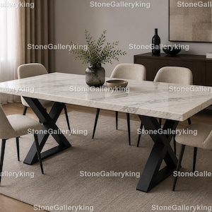 Könnte beinhalten: Ein rechteckiger Esstisch aus Marmor mit einer weiß-grau geäderten Oberfläche, getragen von schwarzen Metallbeinen in X-Form. Sechs beige gepolsterte Stühle mit schwarzen Beinen umgeben den Tisch. Eine Vase mit Grün und eine dekorative Schale stehen auf dem Tisch.