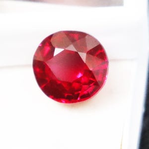 May include: A white ceramic mug with a black handle and the text "But First, Coffee" in a black, bold font. The mug is on a white surface. The mug is approximately 10 cm tall.