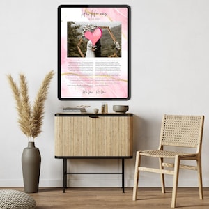 May include: A framed wedding print with a pink and gold watercolor design. The print features a photo of a couple under a floral arch, a pink heart, and the text "His Her was 18.08.2023". The print is displayed on a black tablet.