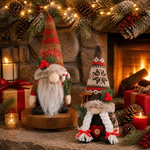 Op de afbeelding: Twee decoratieve kabouterfiguren met hoge gebreide mutsen in rood, bruin en wit. Eén kabouter heeft een lange witte baard en houdt een zuurstok vast, de andere heeft wit gevlochten haar, een rood hartje en een knoop als detail.