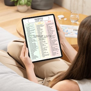 May include: A tablet displaying a "Probiotic Food List" with categories: Eat, Limit, and Avoid. The list includes various food items, such as yogurt, cheese, and vegetables. The tablet is held by a person.
