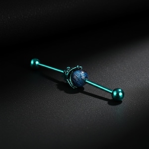 May include: A teal industrial barbell earring with a dark blue and white marbled stone center. The barbell has a ball on each end and a decorative cage around the stone. The jewelry is set against a dark background.