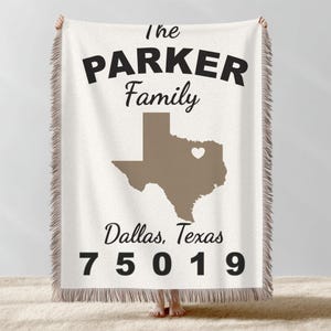 May include: Cream-colored throw blanket with the text "The Parker Family" in black. A brown outline of Texas with a heart is centered below the text. The words "Dallas, Texas" and the zip code "75019" are printed below the Texas outline.