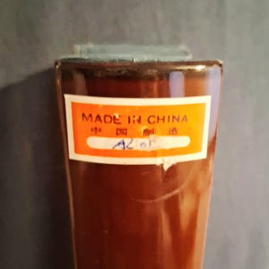 May include: A brown, rectangular object with a label that reads "MADE IN CHINA" in English and Chinese characters. The label is orange with a white border. The object has a slightly textured surface.