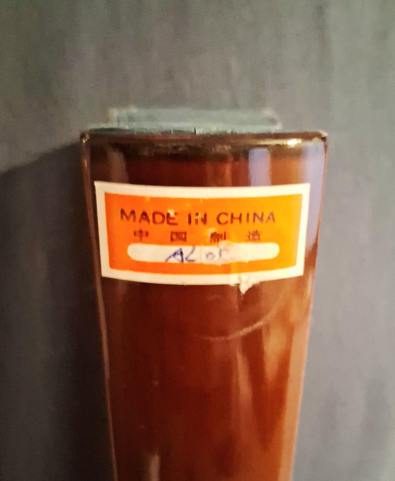 May include: A brown, rectangular object with a label that reads "MADE IN CHINA" in English and Chinese characters. The label is orange with a white border. The object has a slightly textured surface.