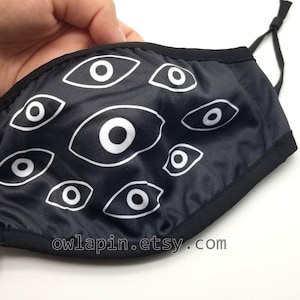Máscara facial arrepiante com estampa de olhos agrupados e bolso para filtro.