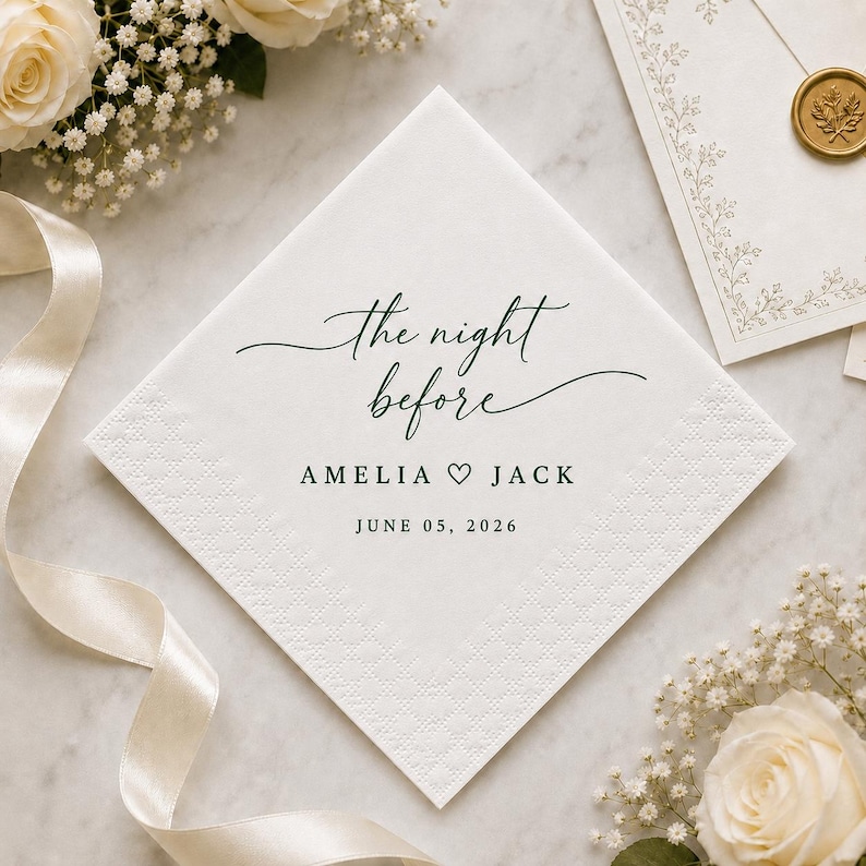 May include: A square white paper napkin featuring dark green text that reads the night before, followed by the names AMELIA and JACK separated by a heart symbol, and the date JUNE 05, 2026. The napkin has a textured border and a smooth centre.