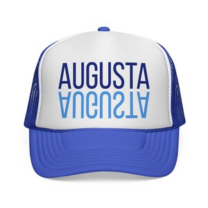 Può includere: Cappellino da camionista blu e bianco con la scritta "AUGUSTA" in blu, con una versione speculare della parola sottostante. Il cappello ha una visiera blu e un pannello frontale bianco, con rete blu sui lati e sul retro.