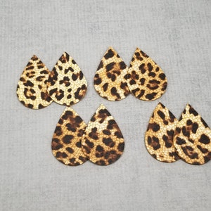 K&ouml;nnte beinhalten: Sechs Paar tropfenf&ouml;rmige Ohrring-Ausschnitte mit Leopardenmuster. Die Ausschnitte sind braun und beige mit dunkelbraunen Flecken, angeordnet auf einer grauen Oberfl&auml;che. Ideal zum Basteln von Ohrringen.