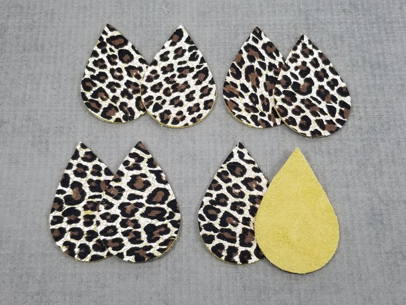 May include: Six teardrop-shaped leather earrings, five with a leopard print pattern in brown, black, and white, and one solid yellow.