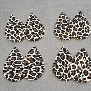 May include: Six pairs of leopard print teardrop shaped earrings. The earrings are made of faux leather and have a gold glitter finish.