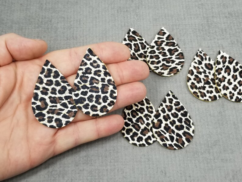 May include: Five pairs of teardrop-shaped earrings with a black and white leopard print pattern.