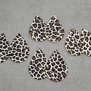 May include: Six teardrop-shaped earrings with a leopard print pattern. The earrings are made of faux leather and have a gold glitter finish.