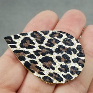 May include: A teardrop-shaped piece of leather with a brown, black, and white leopard print pattern.