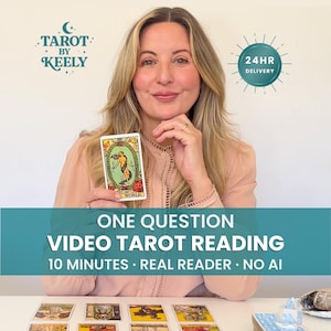 Op de afbeelding: Een persoon houdt een Wereld-tarotkaart vast met de tekst Tarot by Keely, 24hr Delivery, en One Question Video Tarot Reading 10 Minutes Real Reader No AI. Verschillende tarotkaarten liggen uitgespreid op de tafel voor de persoon.