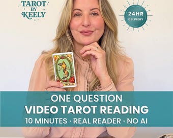 Op de afbeelding: Een persoon houdt een Wereld-tarotkaart vast met de tekst Tarot by Keely, 24hr Delivery, en One Question Video Tarot Reading 10 Minutes Real Reader No AI. Verschillende tarotkaarten liggen uitgespreid op de tafel voor de persoon.
