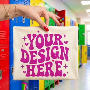 May include: A cream-colored tote bag with the text "YOUR DESIGN HERE" in a vibrant pink, retro font. The design includes stars and hearts. The bag is held in front of a colorful locker background.