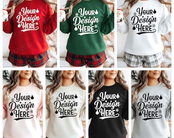 May include: A selection of sweatshirts in different colours, each displaying the text "Your Design Here" in a festive font with snowflake and ornament details. The sweatshirts, in red, green, white, pink, cream, black, and grey, are paired with plaid pajama shorts.