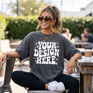 May include: A charcoal gray oversized t-shirt with the text "YOUR DESIGN HERE" in white. The shirt is worn with black leggings and white sneakers. The model is wearing sunglasses and jewelry.