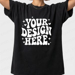 May include: Black t-shirt with the text "YOUR DESIGN HERE" in white, stylized lettering. The design includes stars and hearts. The shirt is a dark, washed-out color, and has short sleeves.