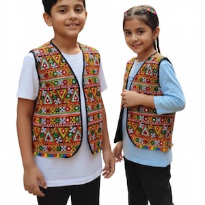 Può includere: Due bambini indossano gilet ricamati colorati con bordo nero. I gilet presentano motivi geometrici in rosso, giallo, verde e blu. Sono abbinati a camicie bianche e azzurre e pantaloni neri.