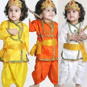 May include: A set of three outfits featuring a long-sleeved tunic with a wrap-style front, a matching dhoti-style bottom, a gold-toned crown, and a beaded necklace. The outfits are shown in yellow, orange, and white, each with a gold polka-dot sash.