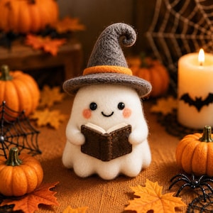 May include: A white felt ghost figurine wearing a grey witch hat with an orange band, holding a small brown book. The ghost has black eyes, a curved mouth, and pink cheeks. It is surrounded by orange pumpkins, autumn leaves, and a candle.