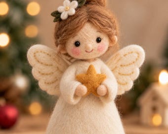 Pode incluir: Uma figura de anjo em lã feltrada com cabelo castanho claro, vestido branco e asas brancas. O anjo tem uma pequena flor branca no cabelo, uma auréola dourada sobre a cabeça e segura uma pequena estrela amarela nas mãos. O rosto tem bochechas rosadas.