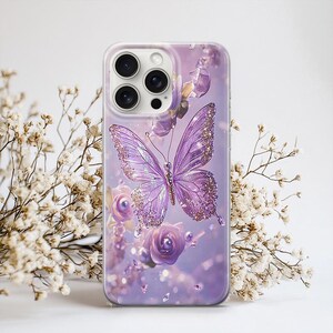 Puede incluir: Funda transparente para tel&eacute;fono con una mariposa morada con detalles brillantes y rosas moradas. El dise&ntilde;o se encuentra sobre un fondo suave y borroso. La funda est&aacute; dise&ntilde;ada para un smartphone.