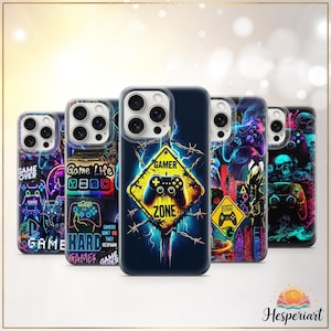 Może przedstawiać: Kolekcja etui na telefony z żywymi wzorami w tematyce gier. Etui mają neonowe kolory, kontrolery do gier i tekst, taki jak "Game Over" i "Gamer Zone". Centralne etui przedstawia żółty znak w kształcie rombu z kontrolerem i napisem "Gamer Zone".