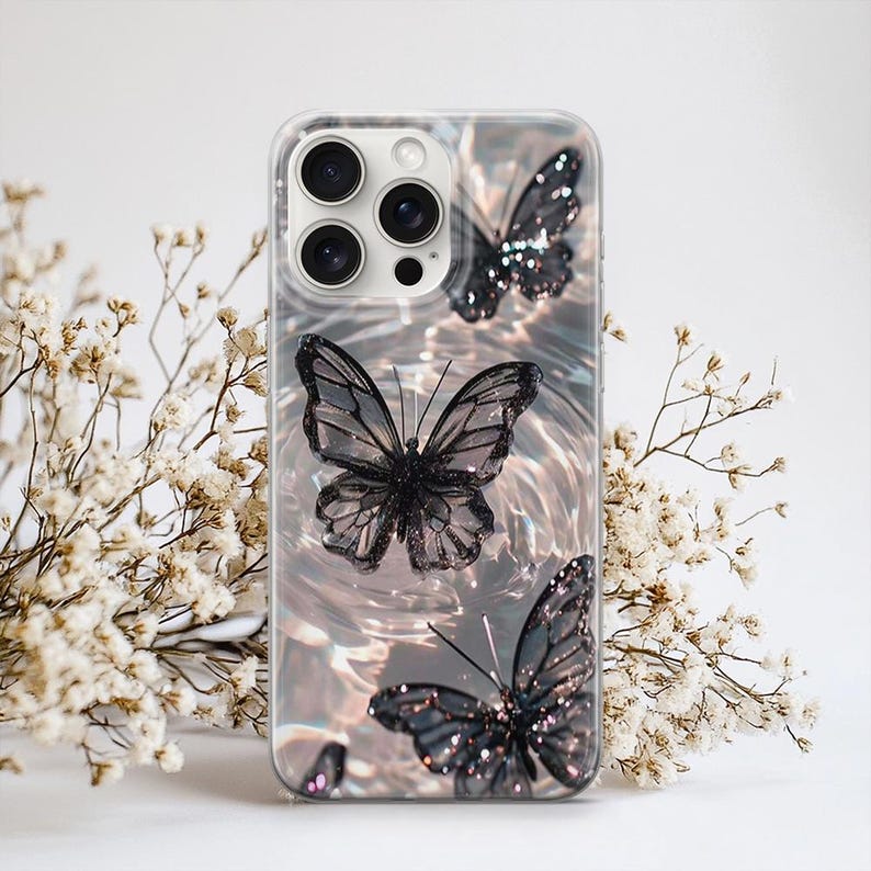 Puede incluir: Funda transparente para tel&eacute;fono con tres mariposas negras con purpurina. Las mariposas tienen patrones de alas detallados sobre un fondo brillante e iridiscente. La funda tiene un borde transparente y un recorte para la c&aacute;mara.