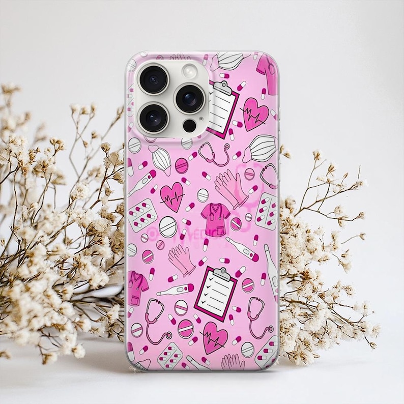 Puede incluir: Una funda de tel&eacute;fono rosa con un patr&oacute;n repetido de ilustraciones m&eacute;dicas. El dise&ntilde;o incluye estetoscopios, pastillas, corazones, batas, guantes y term&oacute;metros. La funda es de material transparente.