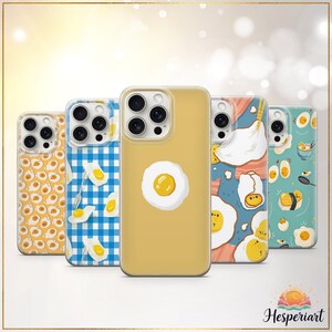 May include: A collection of phone cases with various fried egg designs. The cases feature patterns of eggs, gingham, and abstract art. The color palette includes yellow, blue, and white, creating a playful and appetizing aesthetic. The cases are designed for a smartphone.