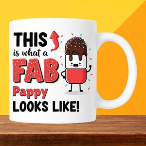 May include: White ceramic mug with the text "THIS is what a FAB Pappy LOOKS LIKE!" in black and red. A cartoon marshmallow character with chocolate and sprinkles is also featured. The mug has a white handle.