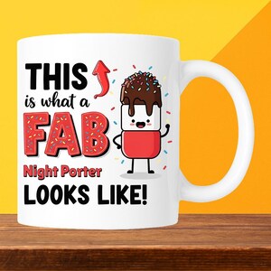 May include: White ceramic mug with a fun design. The mug has the text "THIS is what a FAB Night Porter LOOKS LIKE!" in black and red. A cartoon marshmallow character with chocolate and sprinkles is also on the mug.