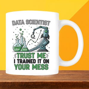 May include: White ceramic mug featuring a data science-themed design. The mug displays the text "DATA SCIENTIST" alongside a robotic arm, rocket, and laboratory flasks. The phrase "TRUST ME I TRAINED IT ON YOUR MESS" is printed below the graphic.