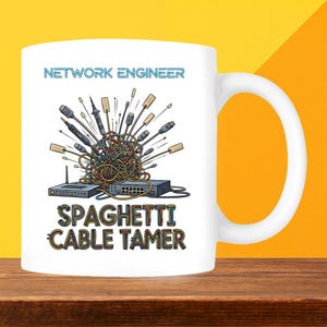 May include: White ceramic mug featuring the text "NETWORK ENGINEER" above a graphic of tangled cables and network devices. Below the graphic, the mug reads "SPAGHETTI CABLE TAMER" in a colourful font. The mug has a large, curved handle.