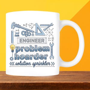 May include: White ceramic mug with a humorous design for engineers. The mug features the word "ENGINEER" above the phrase "problem hoarder solution sprinkler" in blue text. The design includes engineering tools and mathematical symbols.