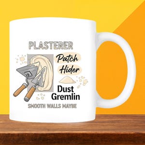 May include: White ceramic mug with a handle, featuring the text "PLASTERER" and the phrases "Patch Hider" and "Dust Gremlin." The mug also displays illustrations of plastering tools and plaster. The phrase "SMOOTH WALLS MAYBE" is also included.