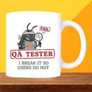 May include: White ceramic mug with a humorous QA Tester design. The mug features a cartoon bug character with a magnifying glass and a "FAIL" sign. Text on the mug reads "QA TESTER" and "I BREAK IT SO USERS DO NOT."