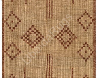 May include: A woven rug with a geometric pattern. The rug features a tan background with a repeating pattern of brown diamonds and vertical stripes. The edges are trimmed with a fringe.