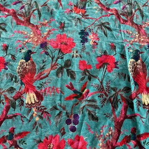 May include: A teal fabric featuring a repeating pattern of birds with red, yellow, and dark blue plumage perched on dark red branches. The design includes large pink and red flowers, dark purple berries, and green leaves throughout the textile.